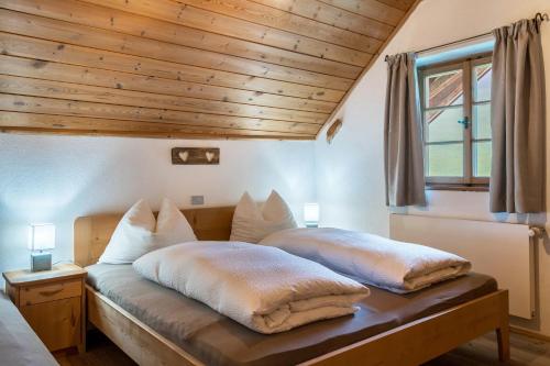 two beds in a bedroom with a wooden ceiling at Ronacherhof Apt Ringelblume in Collalbo