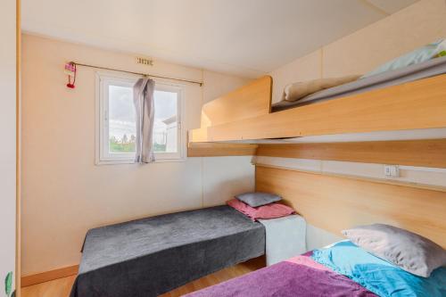 a small room with two bunk beds and a window at Bungalow Azul Profundo in Palmela