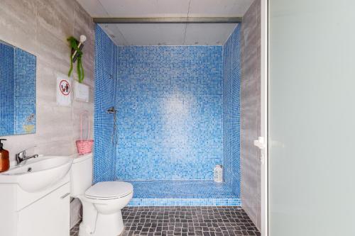 a blue tiled bathroom with a toilet and a sink at Bungalow Azul Profundo in Palmela