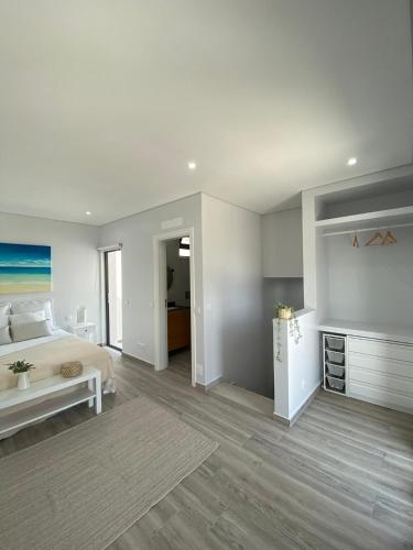 a white bedroom with a bed and a table at Apartment T2 Olhão in Olhão