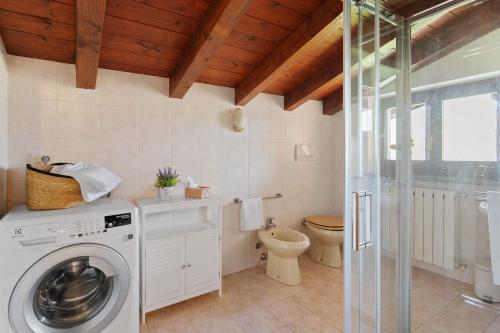 a bathroom with a washing machine and a toilet at Intelvi House in Castiglione dʼIntelvi