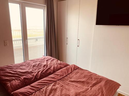 a bedroom with a bed and a large window at Moin Mehrblick in Schillig