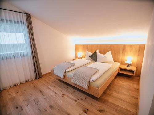 a bedroom with a bed and a large window at Zum Sonnentor App Pinus in Lutago