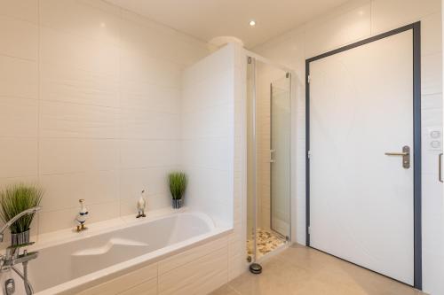 a white bathroom with a tub and a shower at Villa bassin d´archachon in Arès