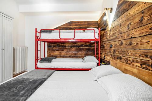 a bedroom with two bunk beds and a wooden wall at Appartamenti Ride Home in Commezzadura