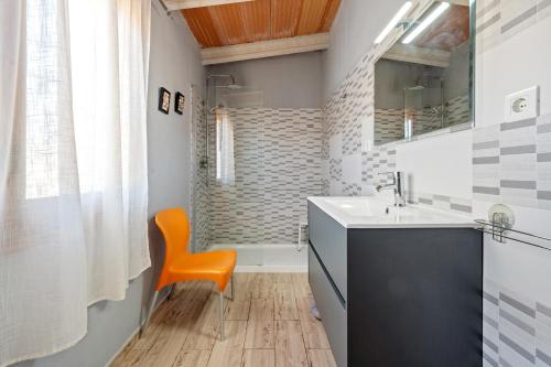 a bathroom with a sink and a orange chair at Can Boquera in L'Ametlla de Mar