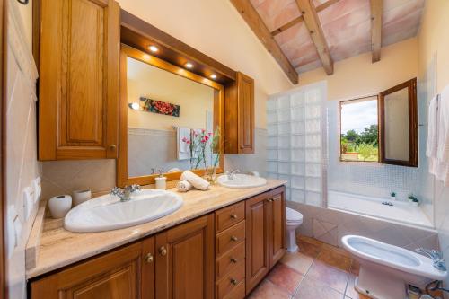 a bathroom with two sinks and a toilet and a mirror at Finca Kelly in Artá