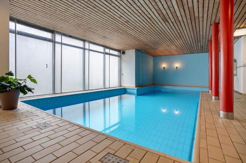 an indoor swimming pool with blue tiles and a red pole at Fewo Talblick mit Schwimmbad in Bad Wildbad