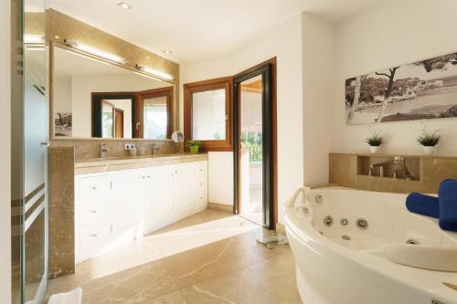 a bathroom with a tub and a sink and a mirror at Finca Playa Llenaire - Can Pou in El Port