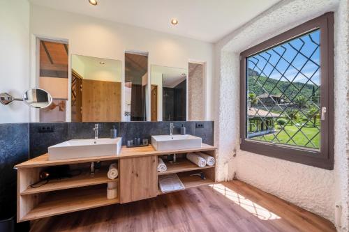 a bathroom with two sinks and a large window at Thanhammer Apt Quarz in Terlano