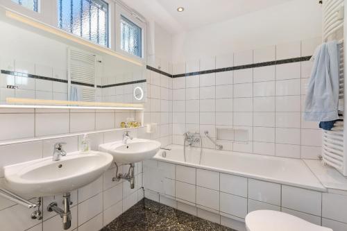 a white bathroom with two sinks and a bath tub at Hegaudomizil in Engen