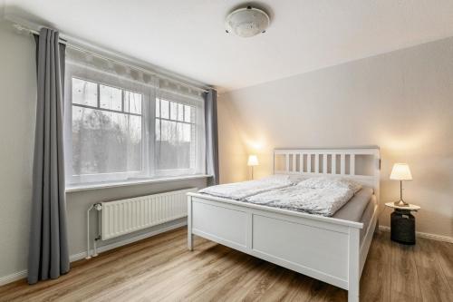 a bedroom with a white bed and a large window at Ferienhaus Nilsson in Heide