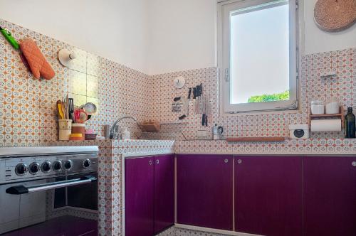 a kitchen with purple cabinets and a window at Il Grifo - Cozy house, wonderful view in Portoferraio