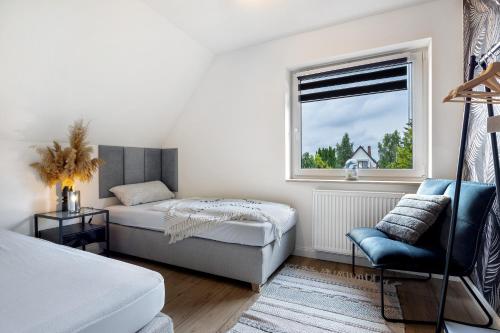a bedroom with a bed and a chair and a window at Penthouse Kokorey in Halstenbek