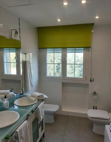a bathroom with two sinks and a toilet and windows at Casa Pablo Picasso 9 in Jimena de la Frontera
