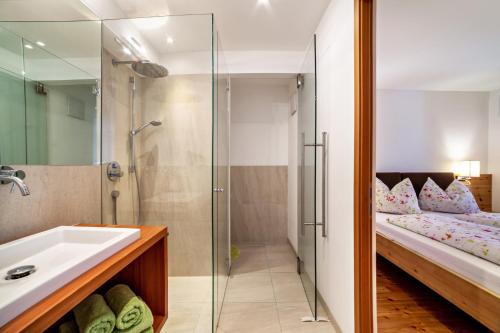 a bathroom with a shower and a sink and a bed at Langstein Wohnung Golden in Coldrano
