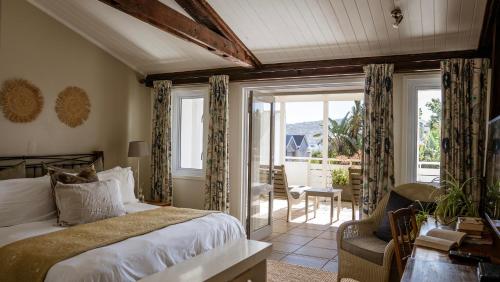 a bedroom with a bed and a chair and windows at The Lofts Boutique Hotel in Knysna