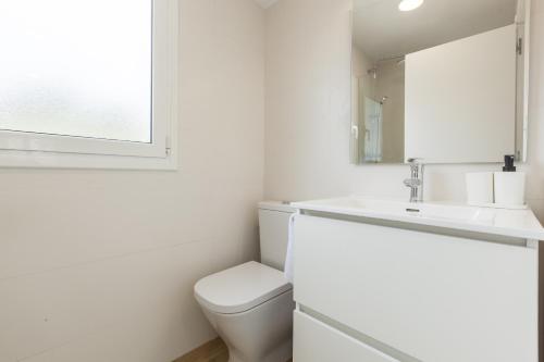 a white bathroom with a toilet and a sink at Casita Palmeras in Canyelles