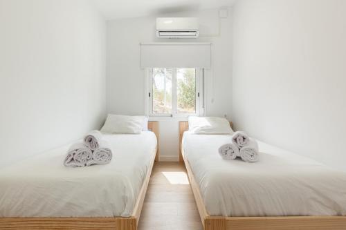 two twin beds in a room with a window at Casita Palmeras in Canyelles