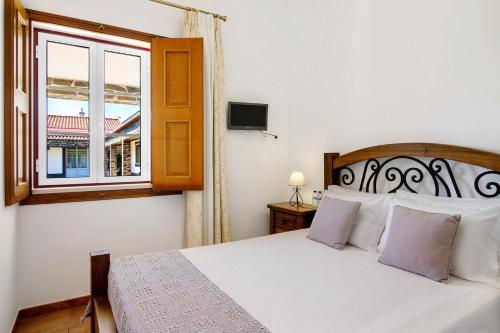 a bedroom with a white bed and a window at Casas do Monte in Giões