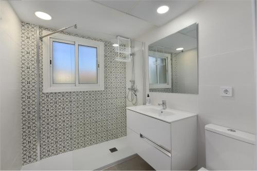 a white bathroom with a sink and a mirror at Fantastic beachfront apartment in Estepona
