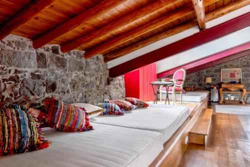 two beds in a room with a stone wall at Ponta da Amora in Ponta Garça