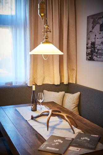 a light hanging over a wooden table with a bottle of wine at Appartements Der Fuchsbau in Saalbach Hinterglemm