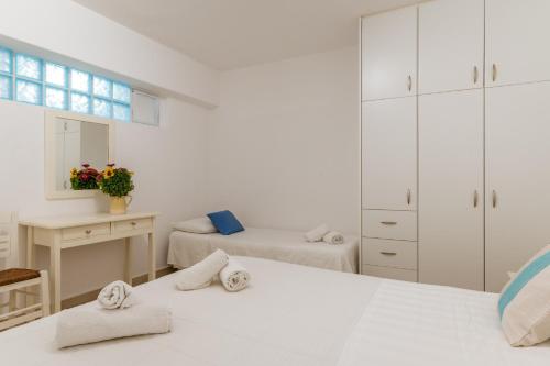 a white bedroom with two beds and a mirror at Afroditi Ftelia Yasemi b in Mykonos