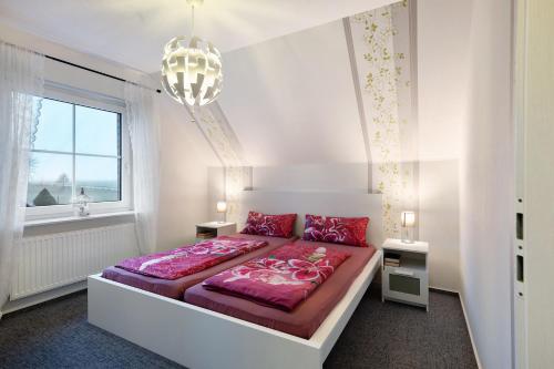 a bedroom with a bed with pink sheets and a chandelier at Ferienwohnung Abendsonne in Lehe