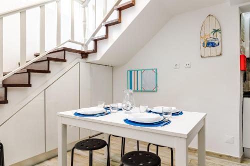 a white dining room with a white table and two stools at Fração D'ouro By Sesimbra in Sesimbra