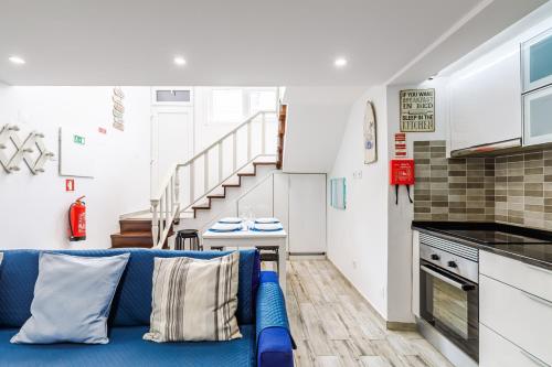 a living room with a blue couch and a kitchen at Fração D'ouro By Sesimbra in Sesimbra