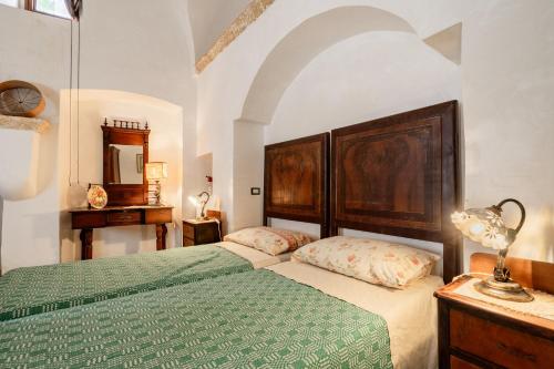 a bedroom with two beds and a table and a mirror at Antica corte dell'800 in Castrignano del Capo