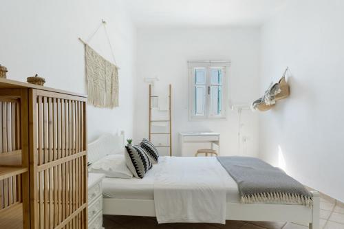 a white bedroom with a bed and a window at Olympos Blue in Karpathos