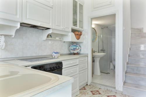 a white kitchen with a sink and a tub at Olympos Blue in Karpathos