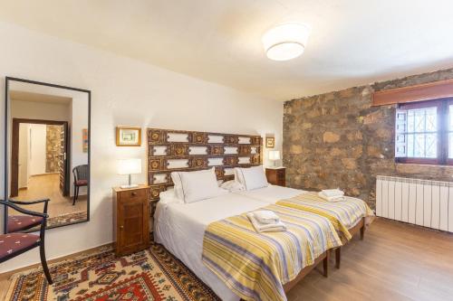 a bedroom with a large bed and a stone wall at Casa Rural Las Yernas in La Serrada