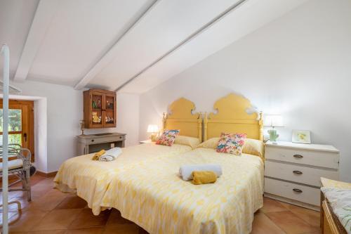 a bedroom with a large bed with a yellow bedspread at Casa Caimari in Caimari
