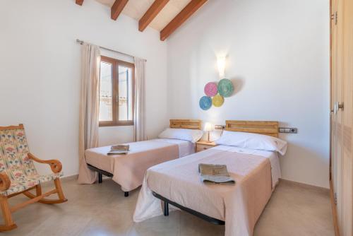 a bedroom with two beds and a chair and a window at Es Campanar in Santanyi