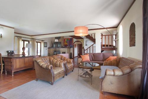 a living room with leather couches and a table at Melquites Country House in Barrantes
