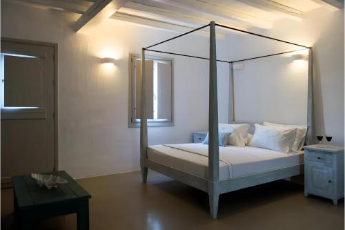 a bedroom with a canopy bed with white sheets and pillows at Echinousa Kimolos katoikia no6 in Kimolos