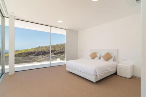 a bedroom with a white bed and a large window at Villa Camacho - Ultra Luxury in Calheta