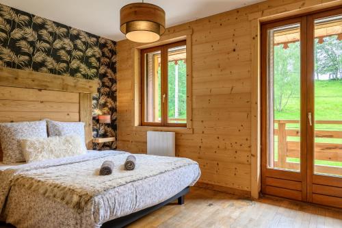 a bedroom with wooden walls and a bed and windows at Chalet le Brusyna avec jacuzzi in Saint-Maurice-sur-Moselle