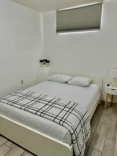 a bed in a white bedroom with a window at Departamento privado in Tijuana