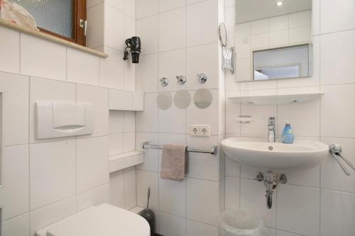 a white bathroom with a toilet and a sink at Gästehaus Heinemann - Og4 in Langenargen