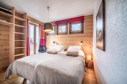 ein Schlafzimmer mit einem weißen Bett, Holzwänden und Fenstern in der Unterkunft Erin Roca immmobilier chatel boude in Châtel