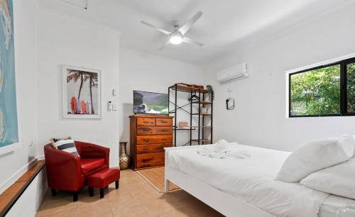 a bedroom with a bed and a red chair at Casa Bella in Bongaree