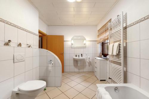 a white bathroom with a toilet and a sink at Fewo Lora in Blankenrath