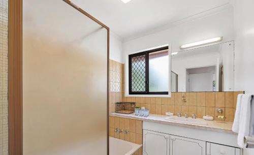 a bathroom with a tub and a sink and a mirror at Casa Bella in Bongaree