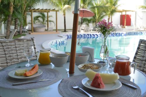 a table with plates of food next to a swimming pool at Master Hotel in Jequié