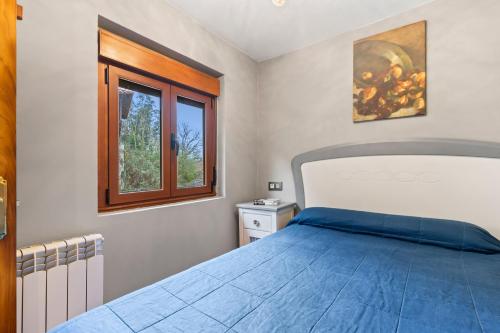 a bedroom with a blue bed and a window at El Bosque in Candamin