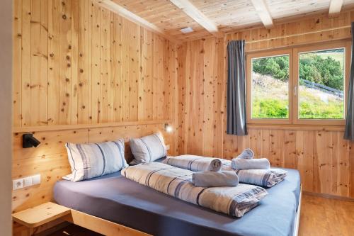 a bed in a wooden room with a window at Almhaus Morgenrast in Sarntal